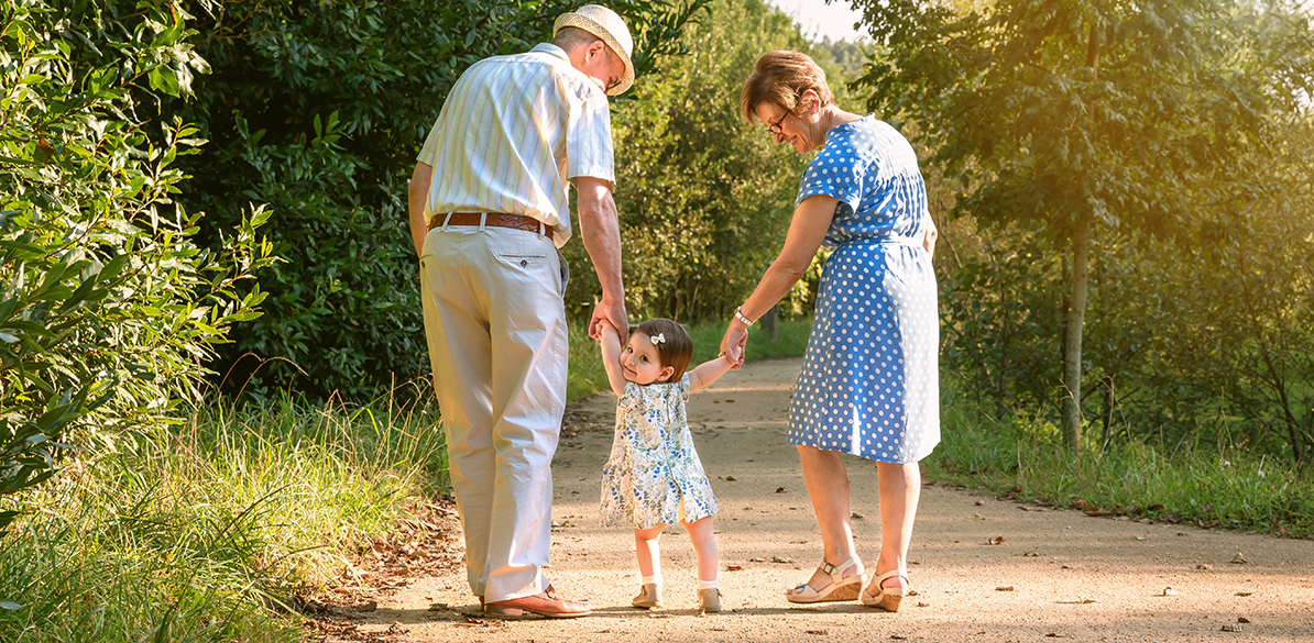Back view of grandparents and baby grandchild walking on a nature path